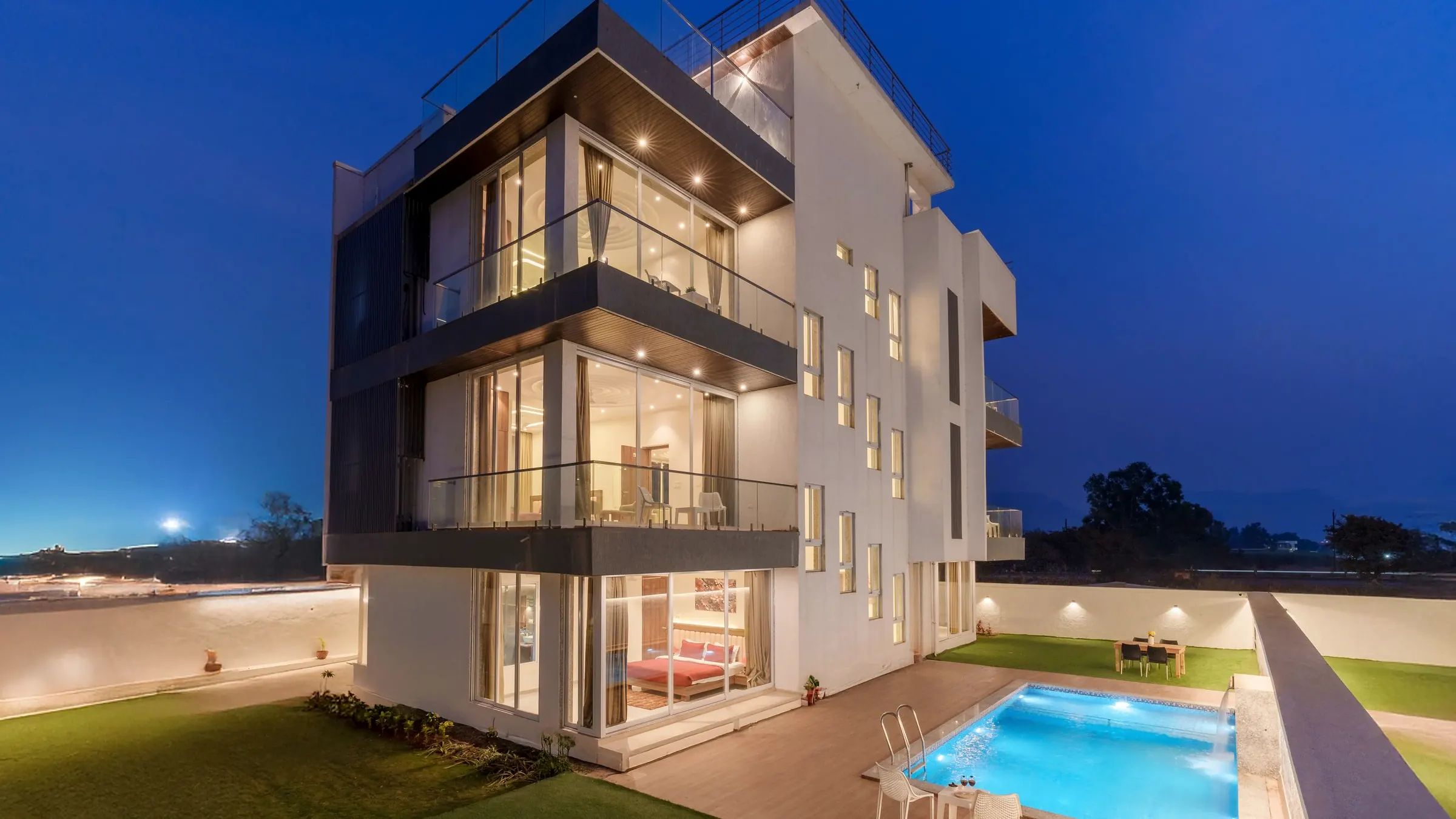 Casa moderna con piscina iluminada al anochecer, obra del estudio